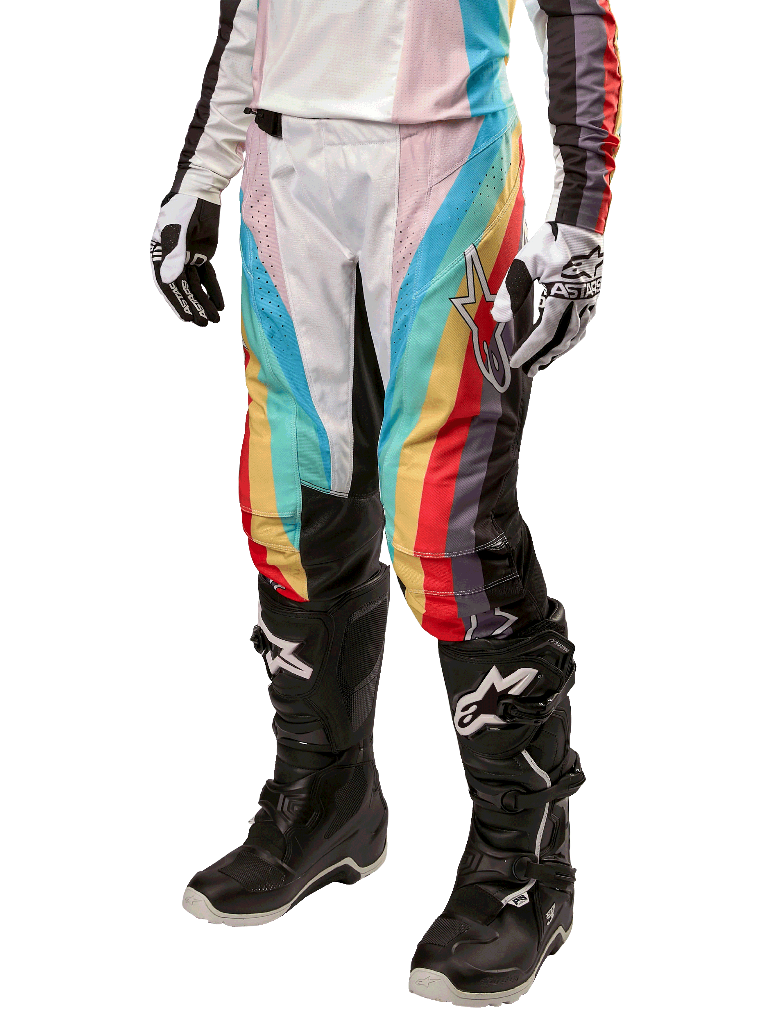 Alpinestars Stella Techstar 2024, pantalon de motocross pour femme, noir multicolore avec rayures diagonales rouges, jaunes et bleues, porté avec des bottes de moto noires et des gants blancs, avec panneaux de protection noirs aux genoux et marquage audacieux pour la course tout-terrain