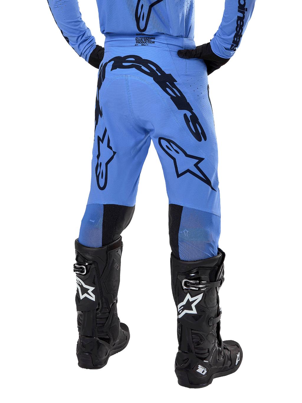 Pantalon Alpinestars Supertech Dade 2024, pantalon de motocross, bleu clair, vue arrière montrant un large marquage noir sur l'assise et les jambes, porté avec des bottes Alpinestars Tech 10 noires, coupe athlétique pour une performance tout-terrain professionnelle.