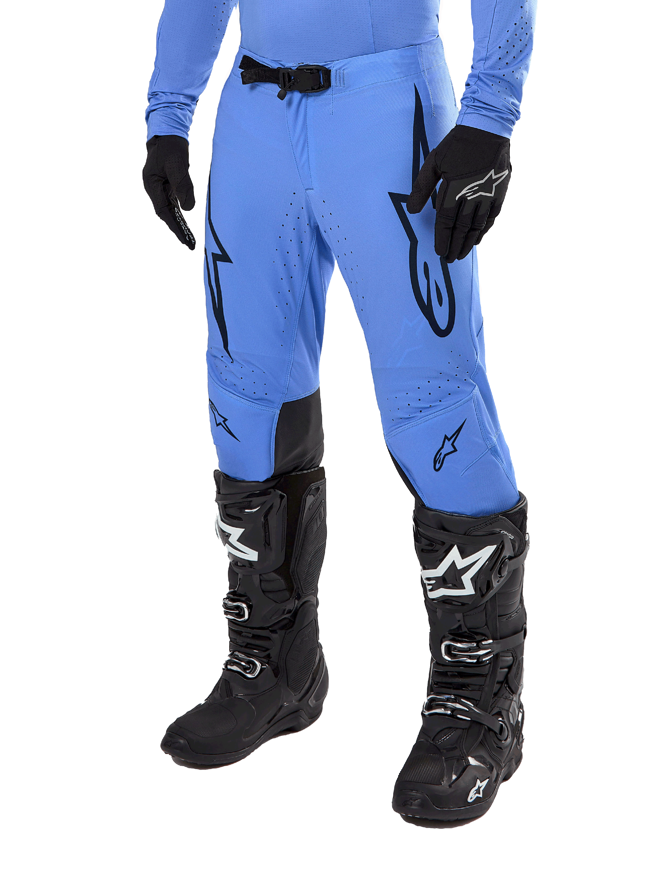 Alpinestars 2024 Supertech Dade Pants, pantalon de motocross, bleu clair avec logos graphiques noirs, avec perforations de ventilation et boucle magnétique à la taille, porté avec des bottes de pilotage techniques et des gants noirs, équipement de course tout-terrain professionnel