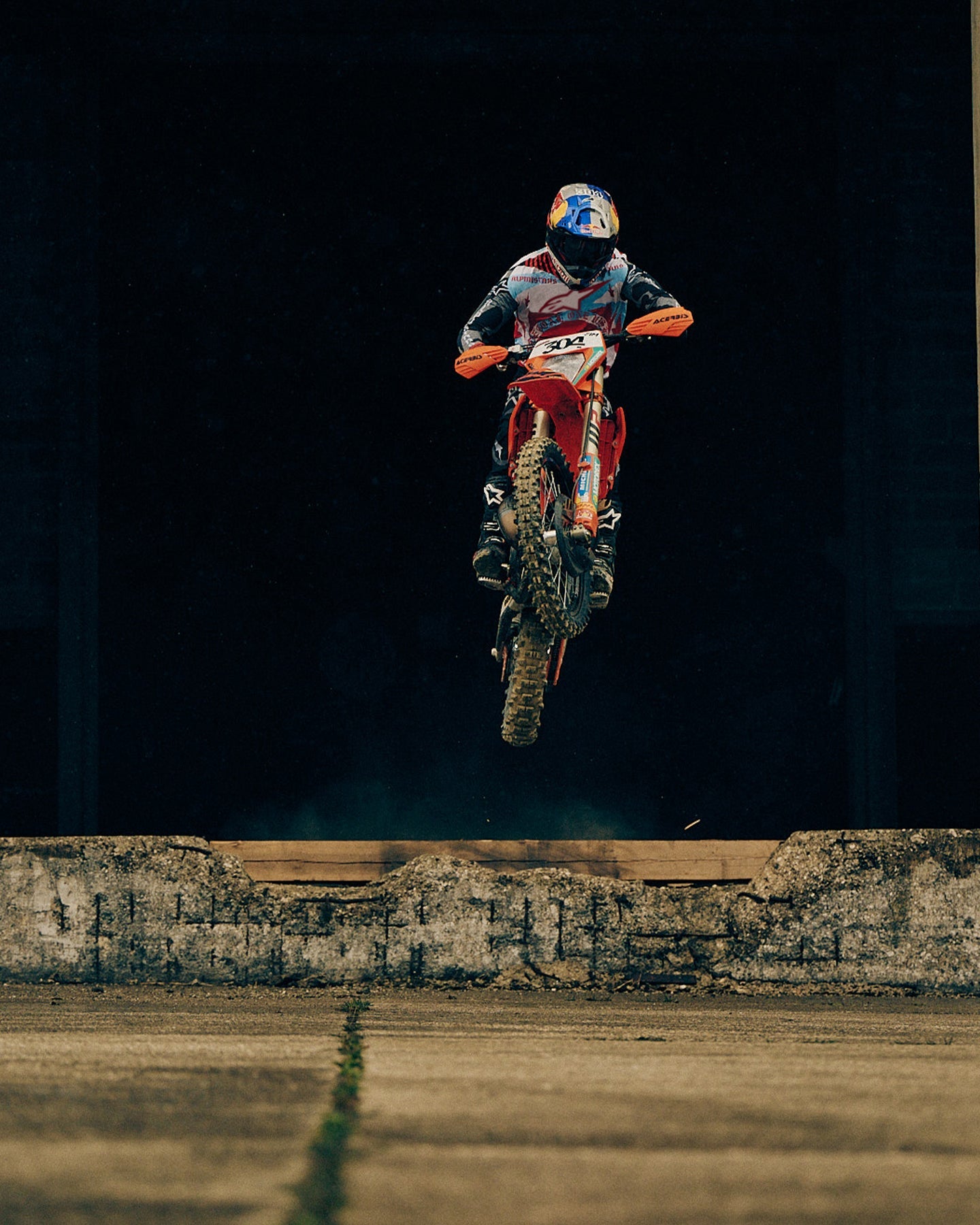 Alpinestars Limited Edition S-M7 Beast Coast Helmet and Visor, light gray and hot orange, worn during a motocross jump.