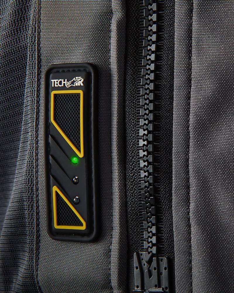 Tech-Air 5 led-display op een donkergrijs textiel vest met een oplichtend groen lampje en een grote zwarte rits.
