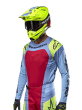 Alpinestars 2024 Techstar Ocuri Jersey, motorcross raceshirt, lichtblauw met rode en neongele accenten, gedragen met bijpassende neongele helm en zwarte crossbril, voorzien van zwarte Alpinestars-logo's op de borst en schouders, atletisch race-geïnspireerd ontwerp voor off-road prestaties