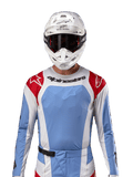 Maillot Alpinestars Techstar Ocuri 2024, maillot de motocross, bleu clair, rouge Mars et blanc, vue de face avec ventilation découpée au laser et coupe athlétique, porté avec un casque blanc et des lunettes pour un look de course tout-terrain professionnel