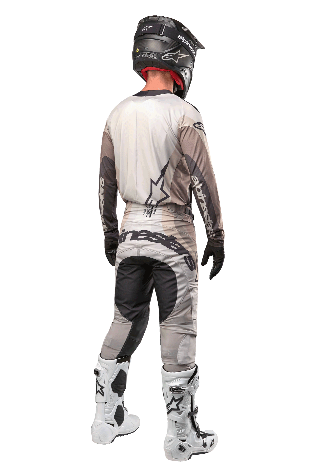 Alpinestars 2024 Techstar Pneuma Pants, pantalon de motocross, sable foncé et gris, vue arrière porté par un pilote avec un maillot assorti, des bottes blanches et noires et un casque noir, avec un marquage Alpinestars imposant sur l'assise et des panneaux sombres renforcés
