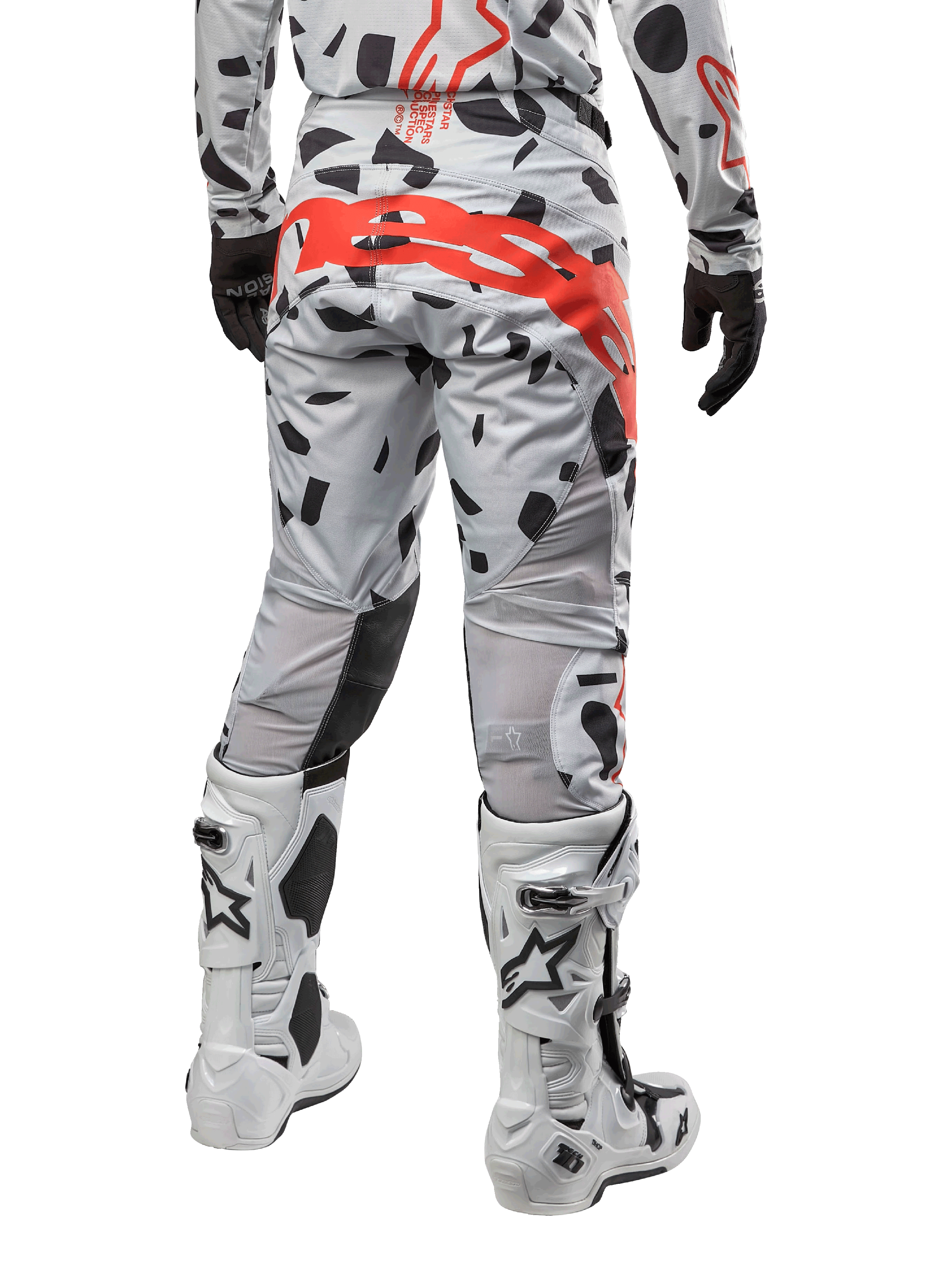 Pantalon Alpinestars Techstar Rantera 2024, pantalon de motocross, Haze Gray Camo avec motifs de camouflage noirs et un grand logo Alpinestars rouge sur l'assise, vue arrière porté avec des bottes blanches et un équipement de course assorti