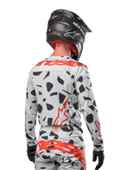 Motocross-Fahrer von hinten im Alpinestars 2024 Techstar Rantera Jersey in Haze Gray Camo, mit einer hellgrauen Basis, schwarzen Grafikflecken und markanten roten Alpinestars-Logos auf dem Rücken und den Schultern, kombiniert mit der passenden Hose und einem schwarzen Helm.