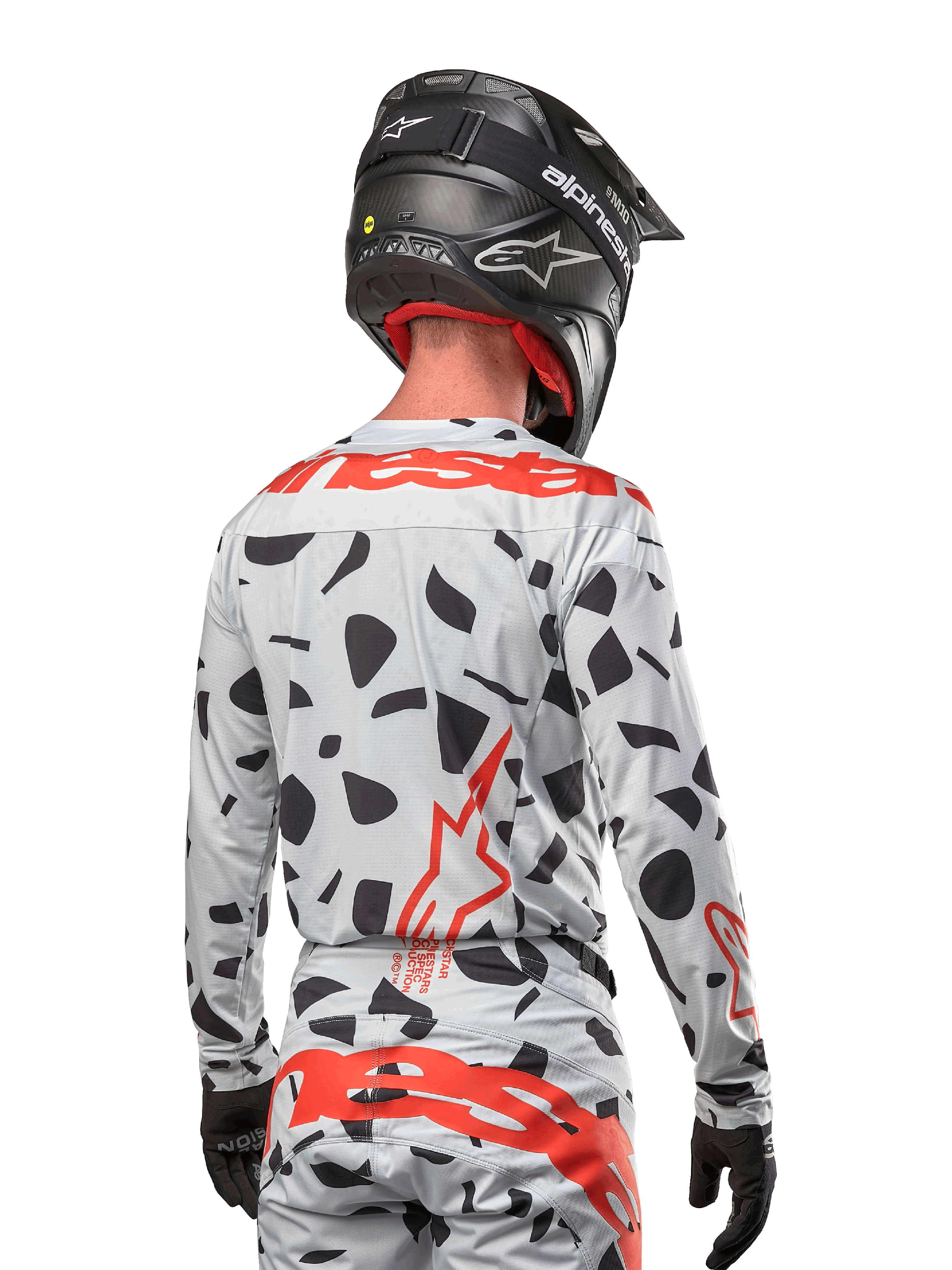 Motocross-Fahrer von hinten im Alpinestars 2024 Techstar Rantera Jersey in Haze Gray Camo, mit einer hellgrauen Basis, schwarzen Grafikflecken und markanten roten Alpinestars-Logos auf dem Rücken und den Schultern, kombiniert mit der passenden Hose und einem schwarzen Helm.