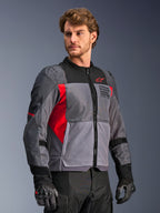 Alpinestars St-2 Air Jacke, Motorradjacke, Dunkelgrau und Anthrazit mit leuchtend roten Akzenten, großflächige Mesh-Belüftungseinsätze, laserperforierte Details, rotes Stern-Logo, von einem Model in einer Studioumgebung getragen, moderner Adventure-Touring-Stil