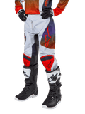 Alpinestars 2024 Youth Racer Hoen Hose, Motocross-Hose, Hellgrau mit Akzenten in Hot Orange und Schwarz, rote Stern-Logos auf den Oberschenkeln und rote Knie-Panels, getragen mit schwarz-weißen Stiefeln, strapazierfähiges Design für Offroad-Rennsport