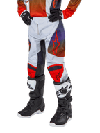 Alpinestars 2024 Youth Racer Hoen Hose, Motocross-Hose, Hellgrau mit Akzenten in Hot Orange und Schwarz, rote Stern-Logos auf den Oberschenkeln und rote Knie-Panels, getragen mit schwarz-weißen Stiefeln, strapazierfähiges Design für Offroad-Rennsport