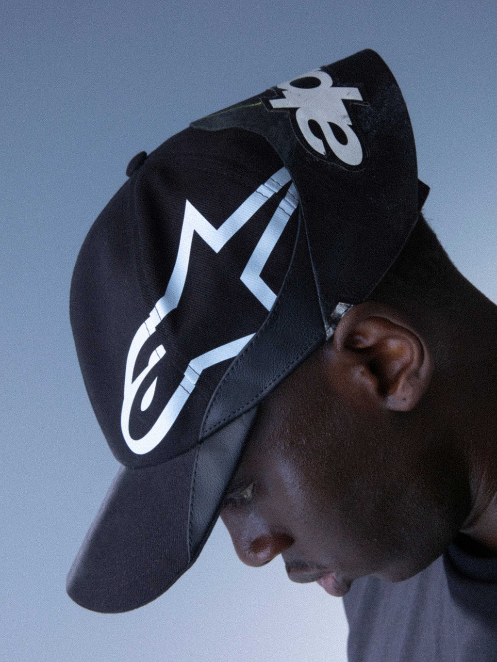 Alpinestars RSRV Resurgence Hat, casquette noire avec logo blanc audacieux, portée par une personne, design streetwear premium