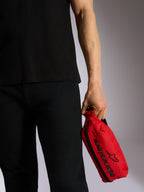 Alpinestars Only Linear heuptas, rood met zwart Alpinestars-logo en woordmerk, vastgehouden door een persoon in zwarte vrijetijdskleding, duurzame polyester heuptas voor stedelijk gebruik